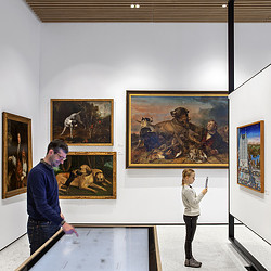 A man and a woman looking at art on the wall.